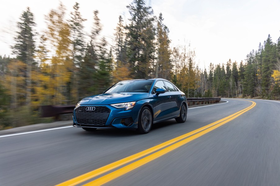 A blue 2022 Audi A3 sedan driving down a tree-lined street