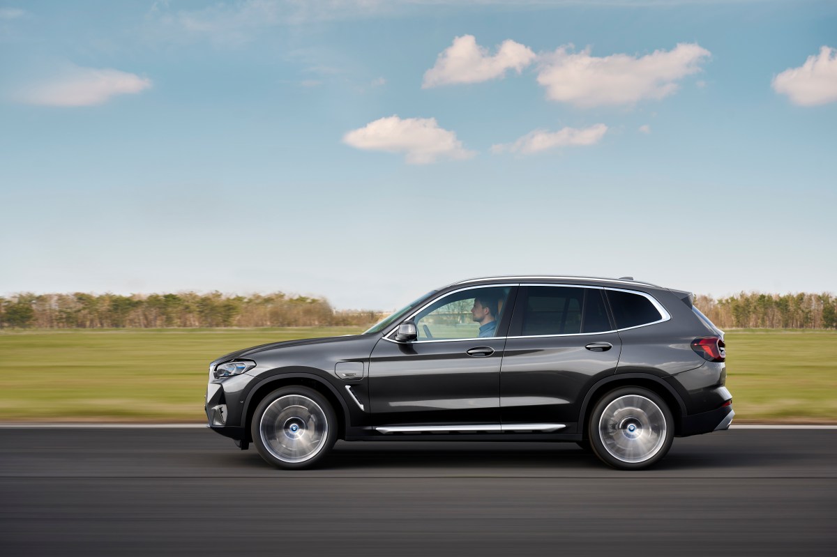 a silver BMW X3 driving by a green field