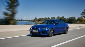 A front view of the 2022 BMW i4 driving down a road.