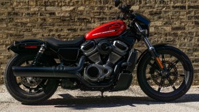 The right-side view of a red-and-black 2022 Harley-Davidson Nightster in front of a brown brick wall