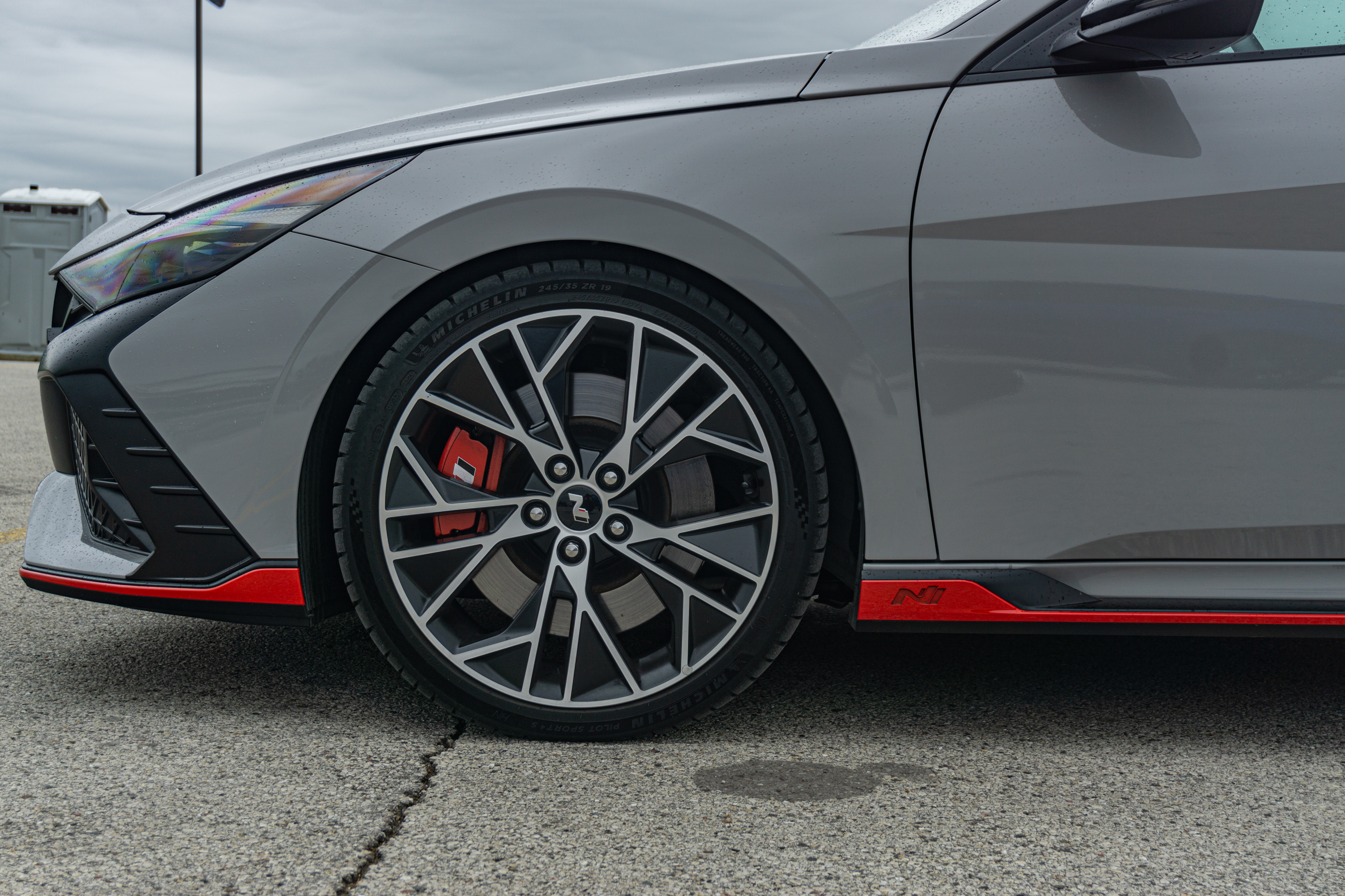 A closeup view of a gray 2022 Hyundai Elantra N DCT's front driver-side wheel and brake