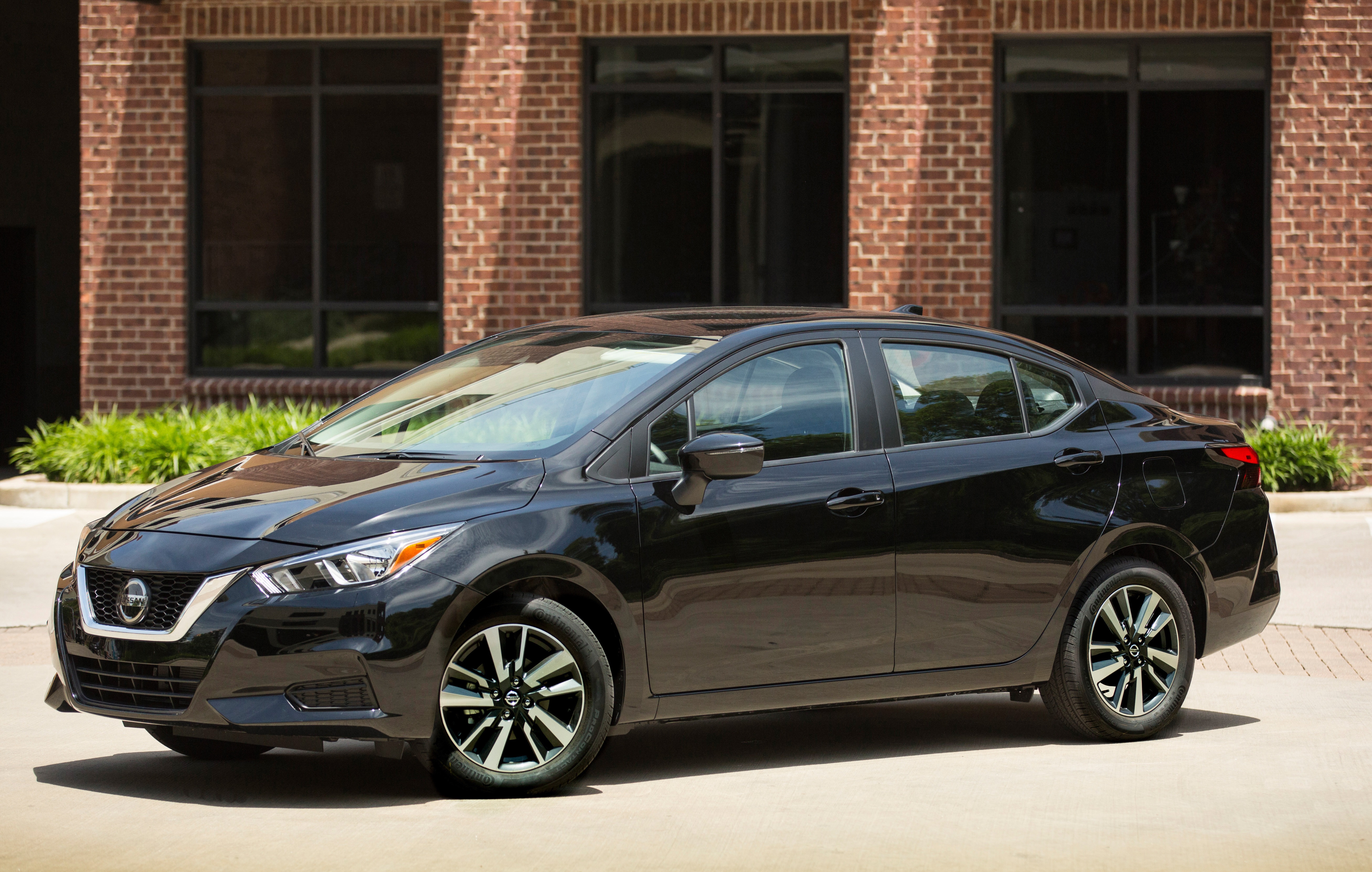 A black 2022 Nissan Versa parked next to a brown building