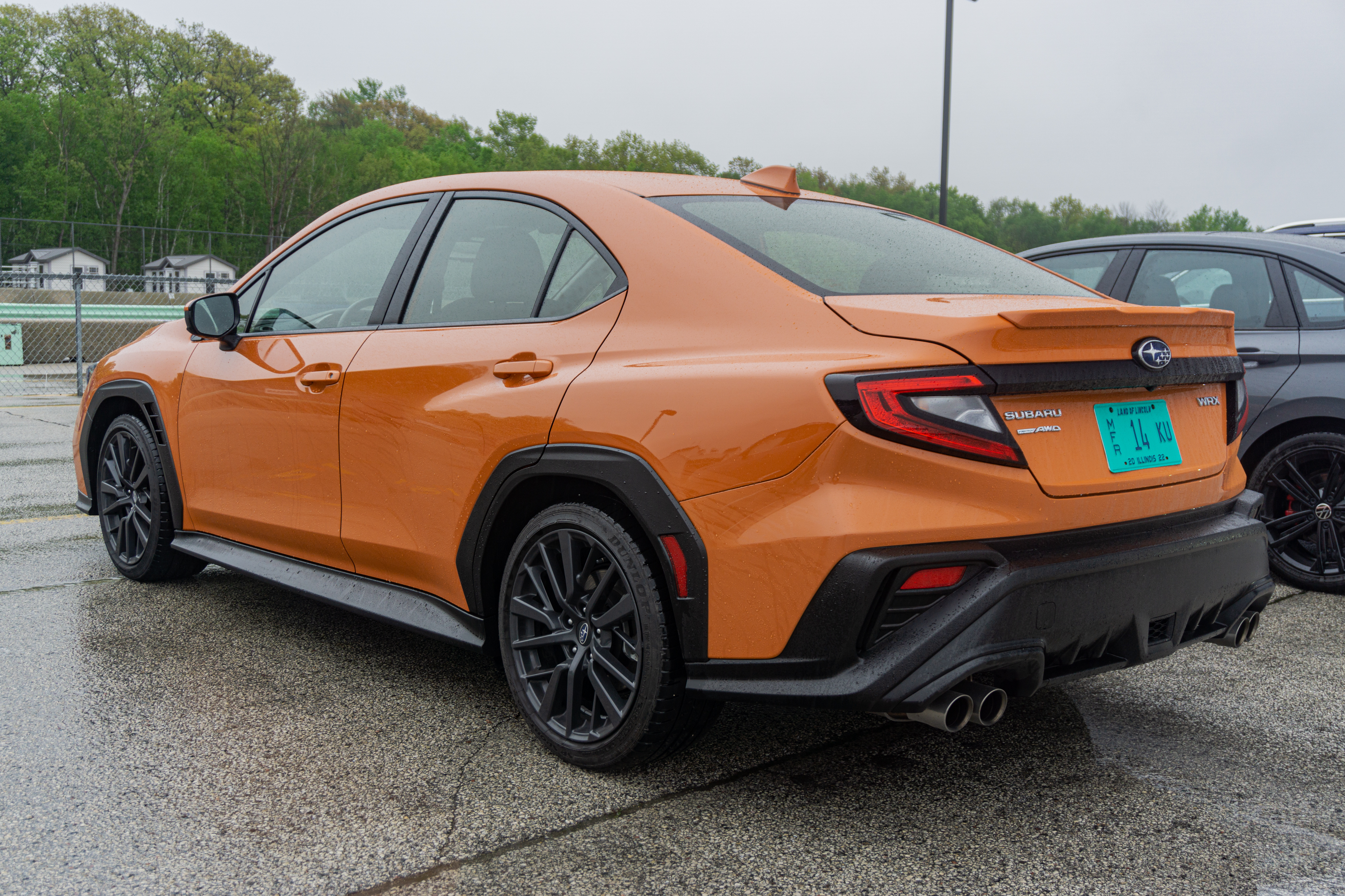 The rear 3/4 view of an orange 2022 Subaru WRX Premium in the Road America parking lot