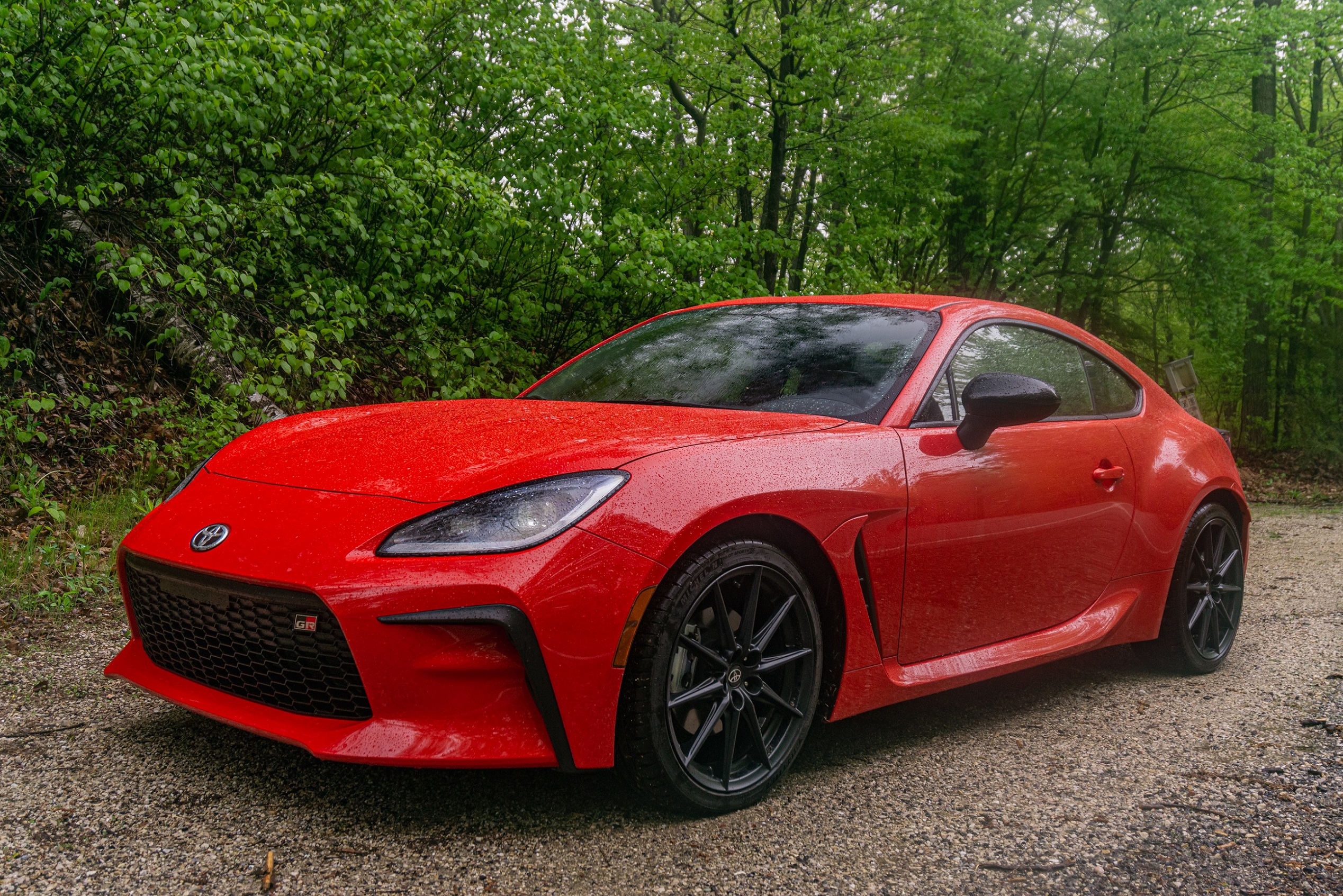 A red 2022 Toyota GR86 Premium on a forest road