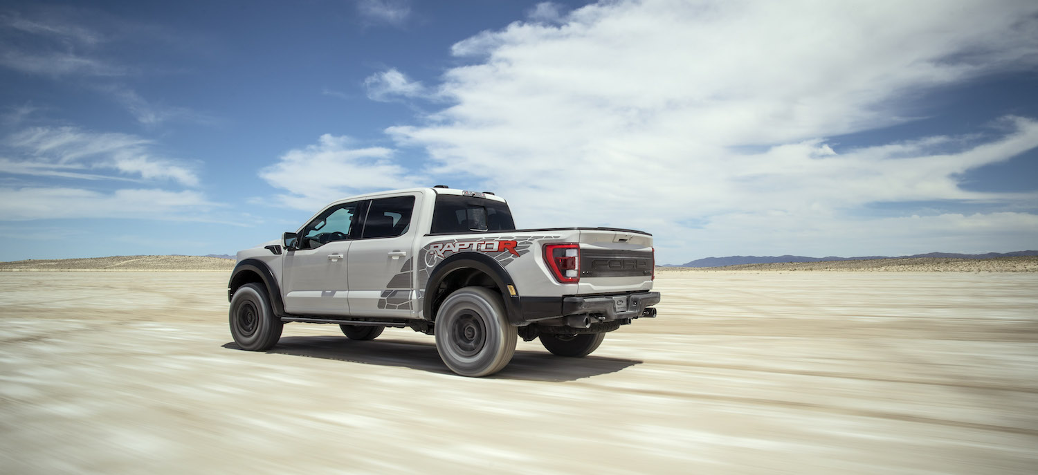 Promo photo of a gray Ford Raptor R truck driving through the desert.