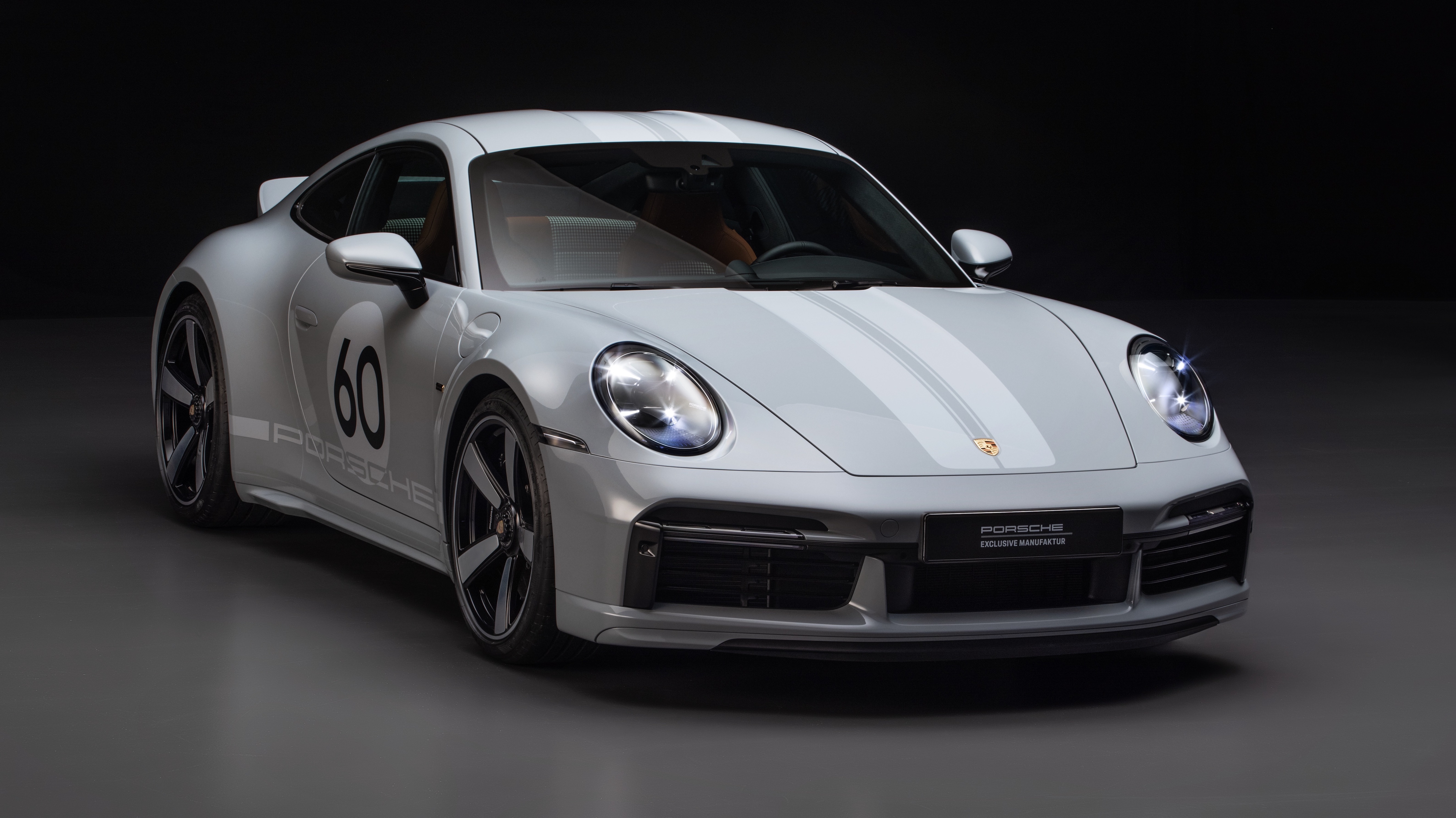 The front 3/4 view of a gray-on-gray 2023 Porsche 911 Sport Classic in a black studio