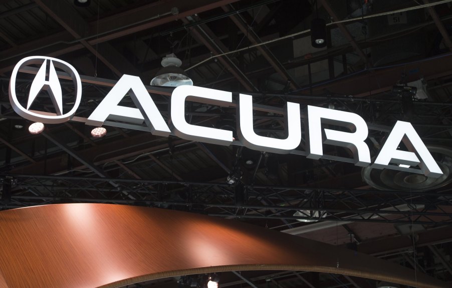 An Acura sign lit up in white on a black background.