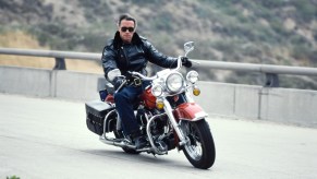 Arnold Schwarzenegger going around a corner faster on a motorcycle.