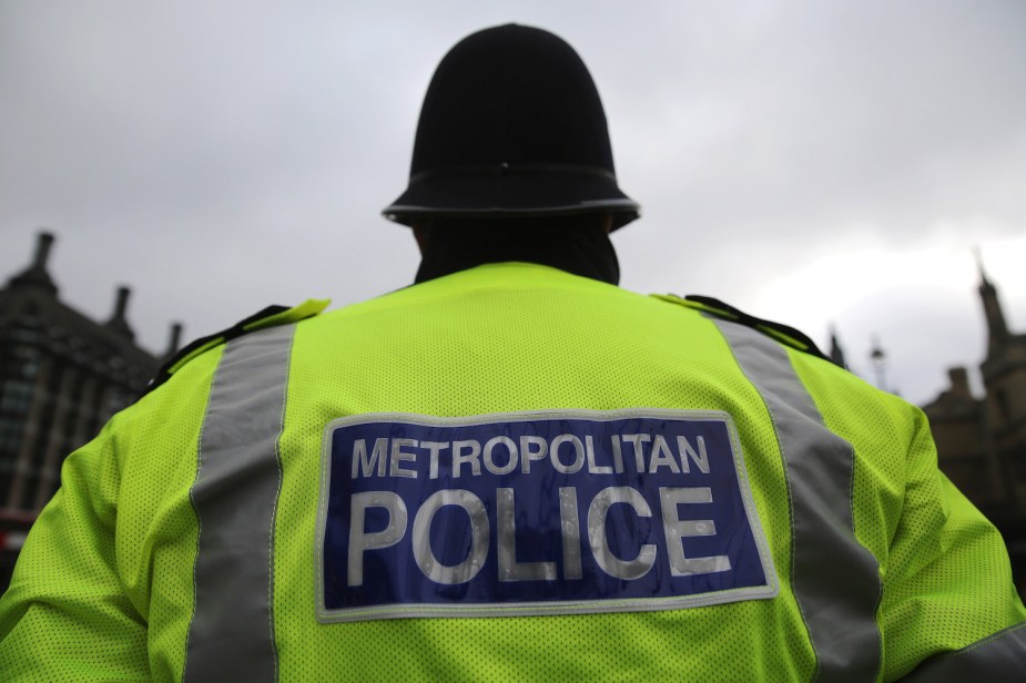 The back of a London police officers, the words Metropolitan Police visible on his bright green jacket.