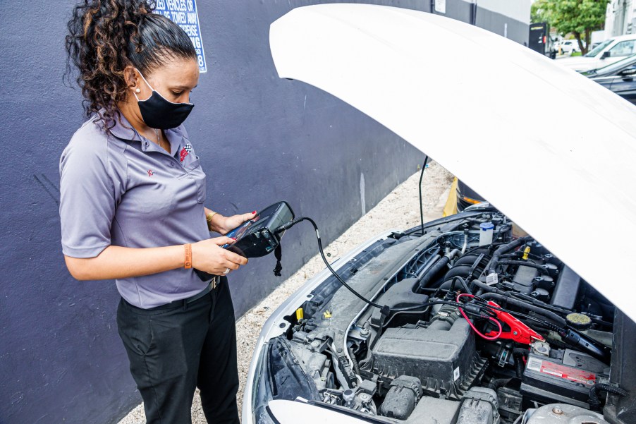 A woman testing a car battery in a parking lot