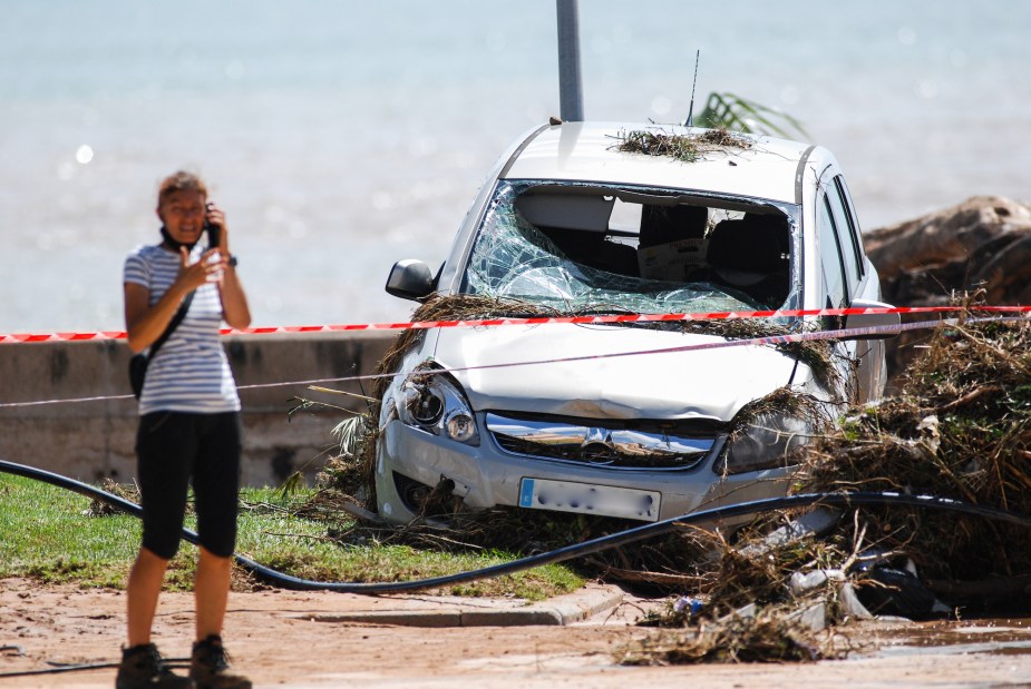 A person potentially feeling the cost of cheap auto insurance after an accident in their white car. 