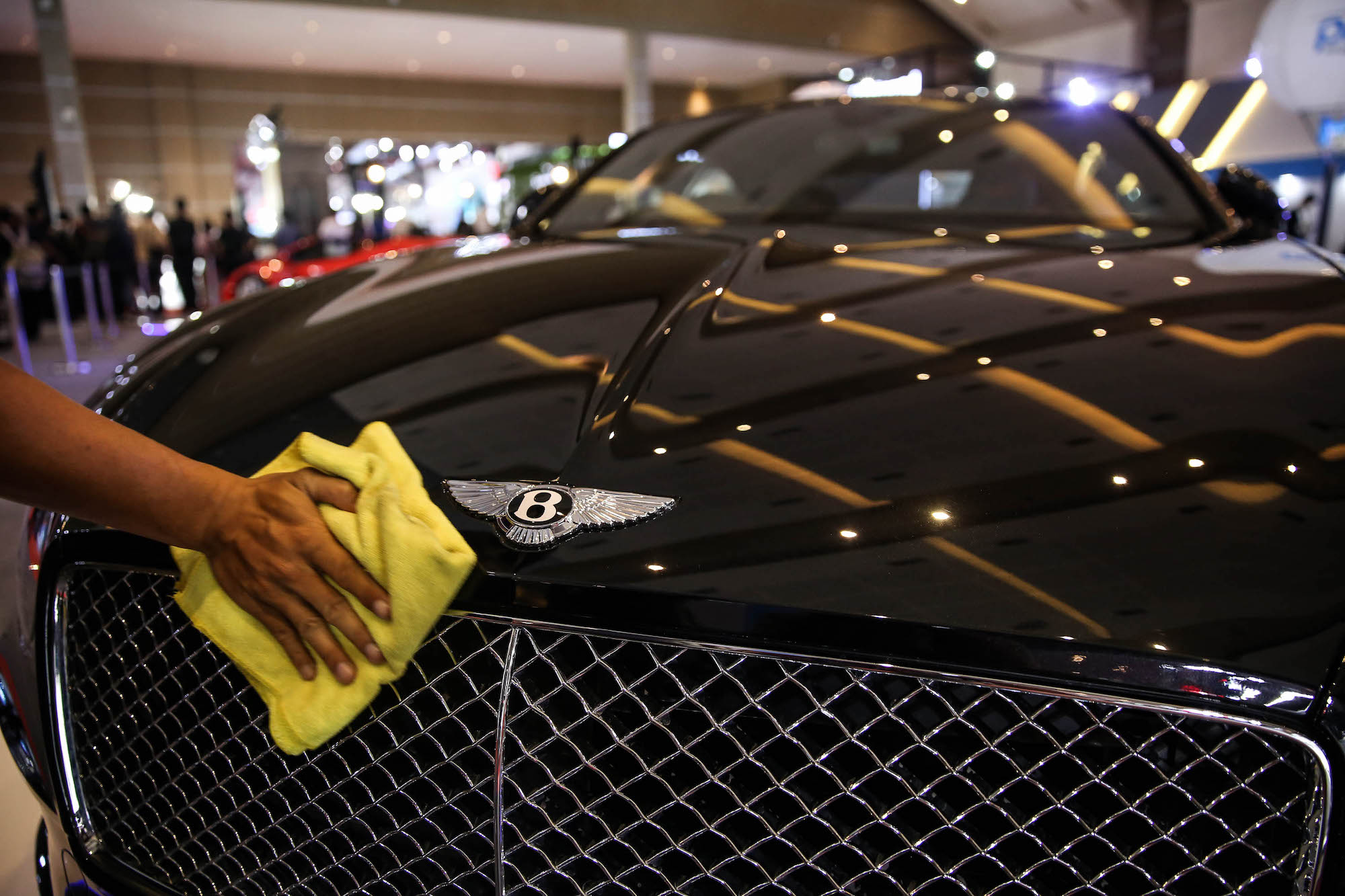 Wash your microfiber towels the right way to achieve high-shine like this person detailing a black Bentley