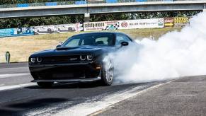 A black 2015 Dodge Challenger SRT Hellcat lights up its tires in a burnout.