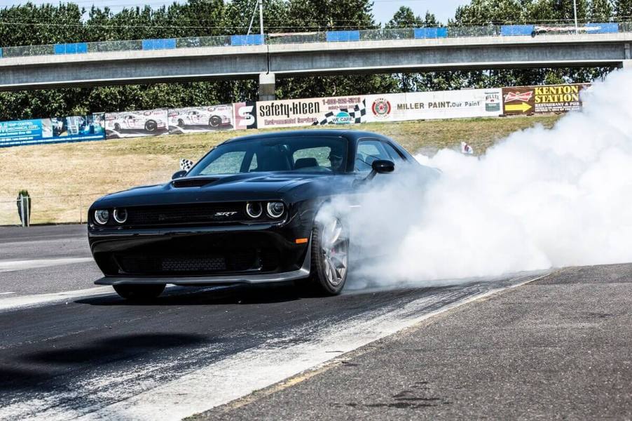 A black 2015 Dodge Challenger SRT Hellcat lights up its tires in a burnout.