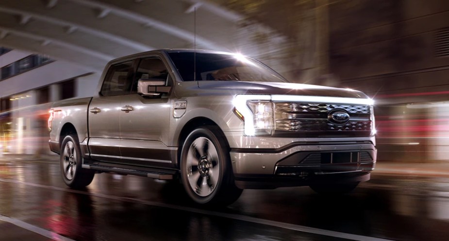 A gray 2022 Ford F-150 Lightning is driving on the road.