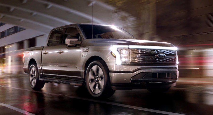 A gray 2022 Ford F-150 Lightning is driving on the road.