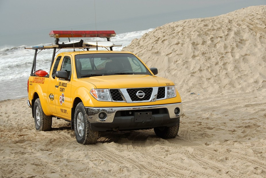 A yellow Nissan Frontier sits on a beach as a used truck.