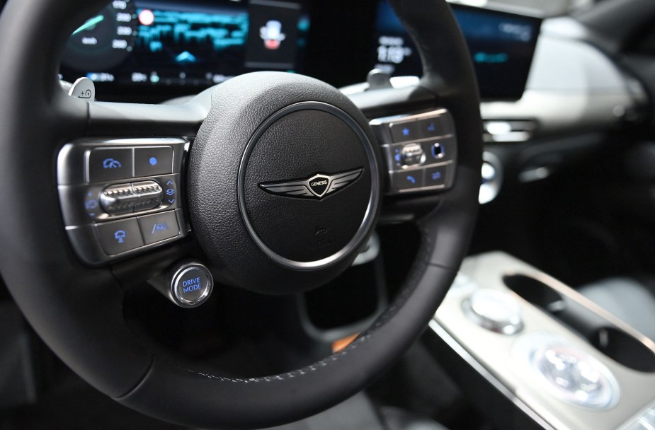 The steering wheel of a Genesis GV60 with black interior. 