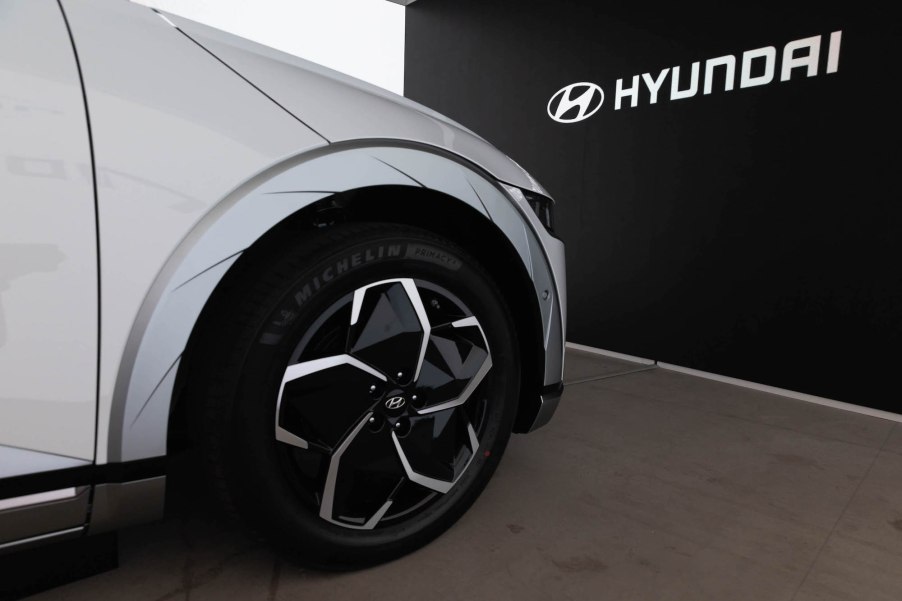 A silver Hyundai parked in front of a black background with Hyundai written on it.