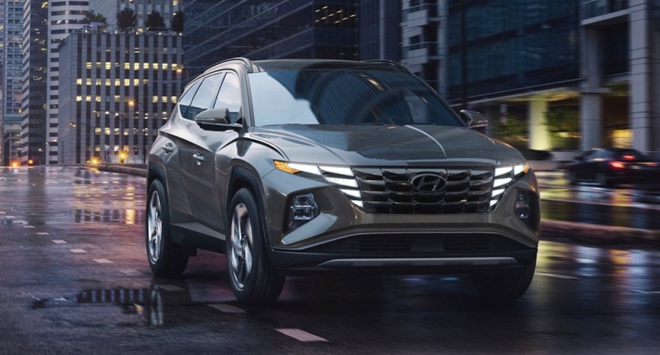 A gray 2022 Hyundai Tucson compact SUV is driving on a wet road.