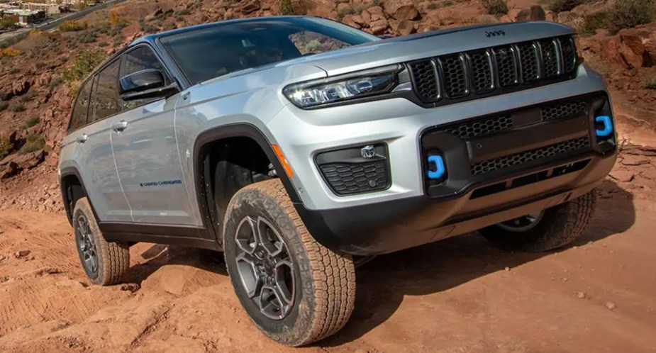 A gray 2023 Jeep Grand Cherokee midsize SUV is driving up a hill. 