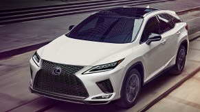 A white Lexus RX350 luxury midsize SUV is driving on the road.