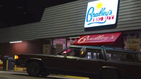 A Mercury Station Wagon turning around on a street at night, a grocery store visible in the background.