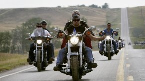 People riding a motorcycle down a straight highway.