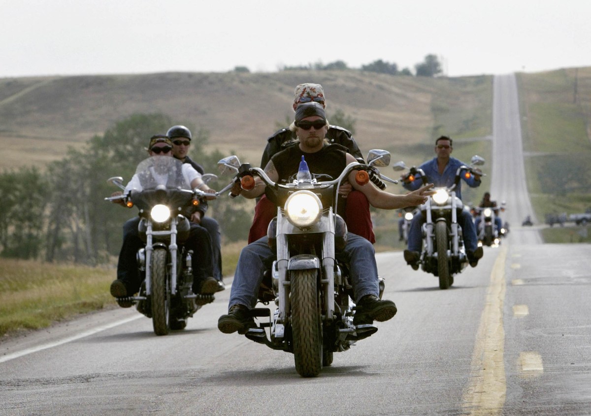 People riding a motorcycle down a straight highway. 