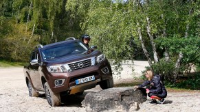 A burgundy colored Nissan Navara-R driving over a rock.