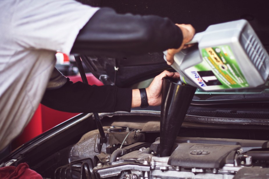 A man performing car maintenance by changing the oil