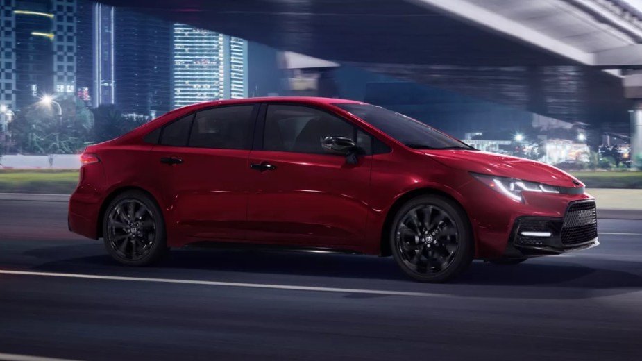 Red 2023 Toyota Corolla driving under a bridge