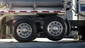 Semi truck lift/drop axle lifted off the ground, gas pumps visible in the background.