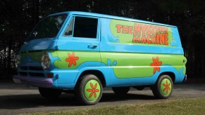 The Mystery Machine van from Scooby-Doo, the best cartoon car of all time, parked near a forest