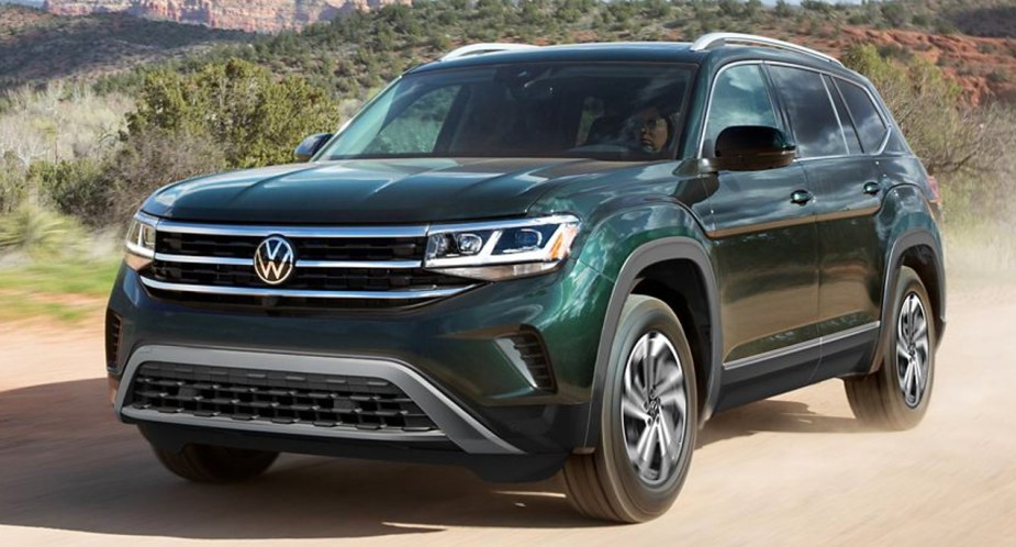 A green 2022 Volkswagen Atlas midsize SUV is driving off-road.