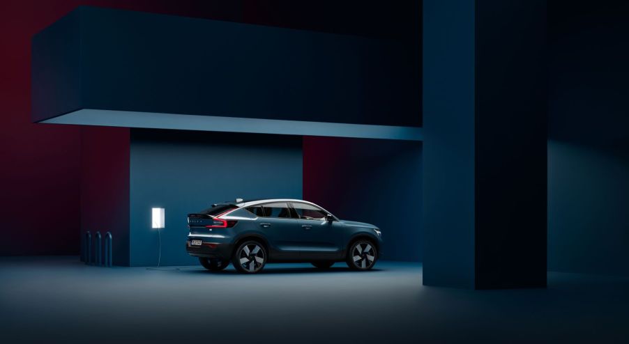 A Volvo C40 Recharge electric SUV model in Fjord Blue charging in a darkened room