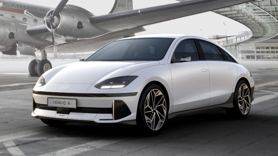 White 2024 Hyundai IONIQ 6 electric sedan parked near an airplane, highlighting its release date and price