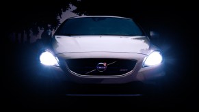 White Volvo car with shining headlights, highlighting reasons why car have two headlights instead of one