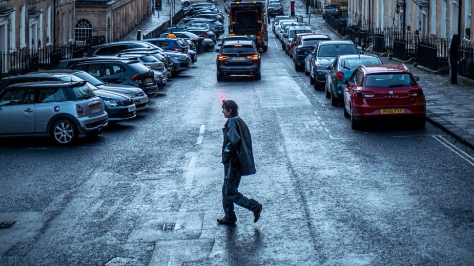 Woman jaywalking across across a narrow street, highlighting whether or not jaywalking is still a crime