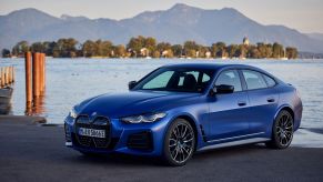 A blue BMW i4 M50 parked on a beach as the tide rises near its rear wheels