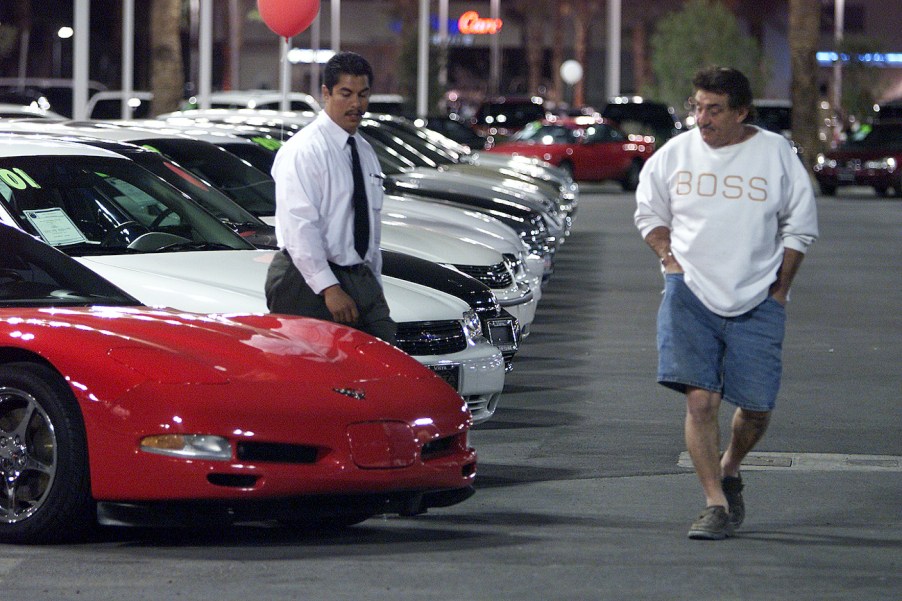 A customer checks out a used Corvette at a dealership.