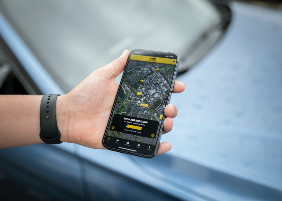 A photo of a man holding a phone with a GPS map on it.