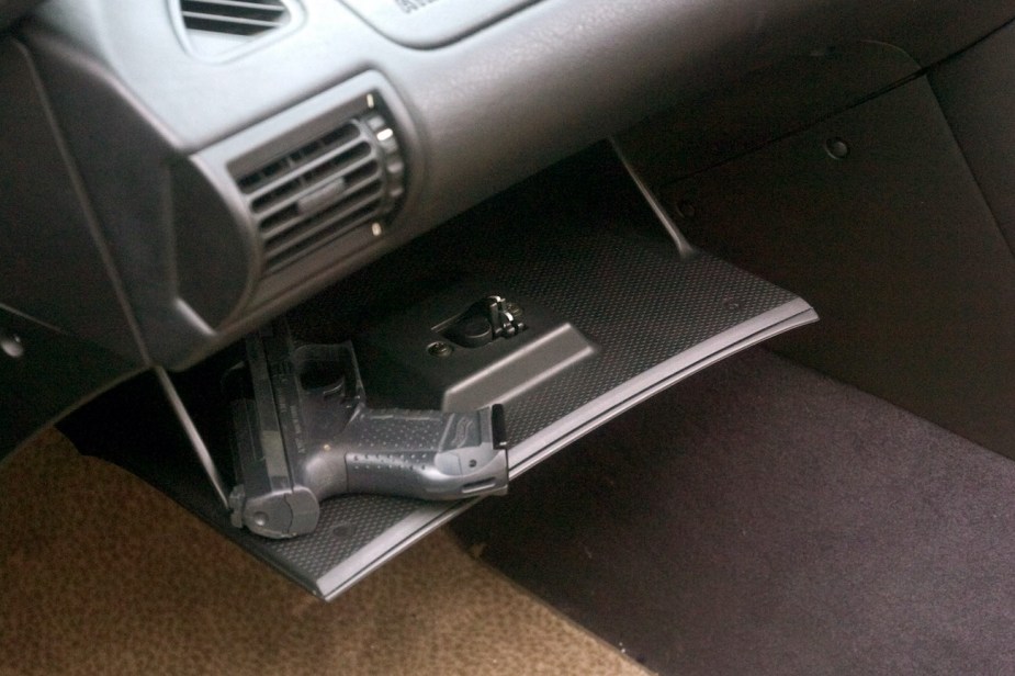 A hand gun in  the glove compartment of a car.