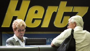 A Hertz worker assists a customer at its rental-car pickup area.