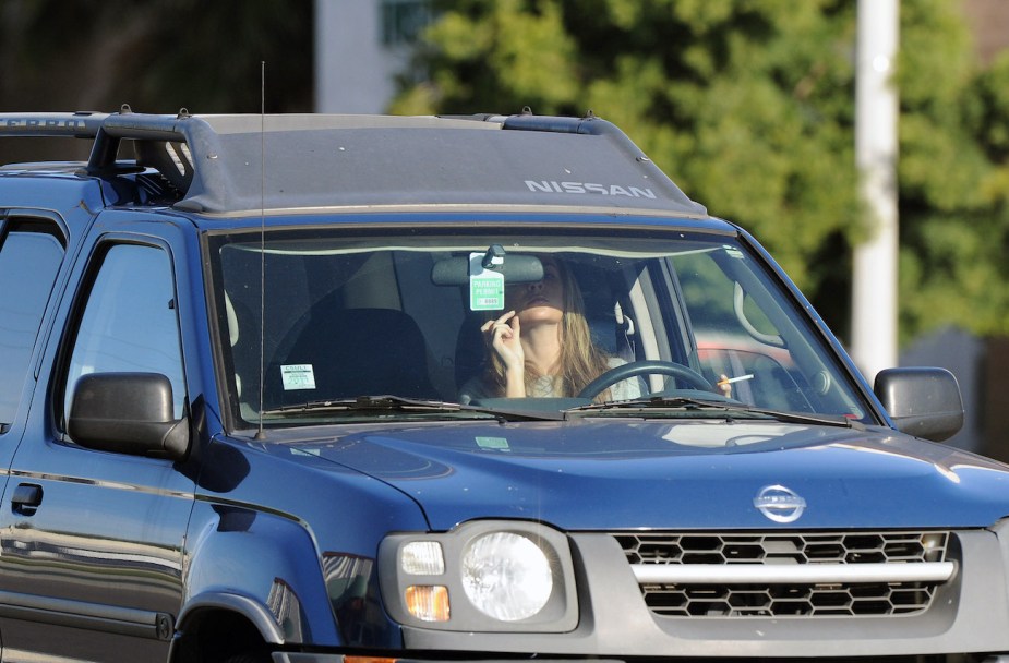 A driving applies makeup in her car while driving on the freeway.