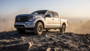 2021 Ford F-150 Tremor full-size pickup truck parked on a rocky mound surrounded by dust clouds