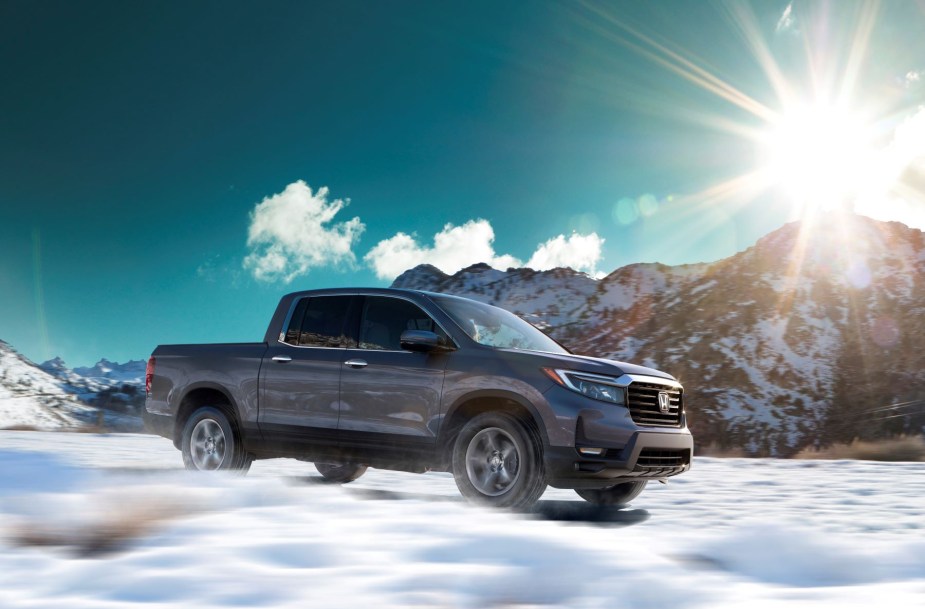 The 2022 Honda Ridgeline RTL-E compact pickup truck driving over a snowy field as the sun rises over a mountain