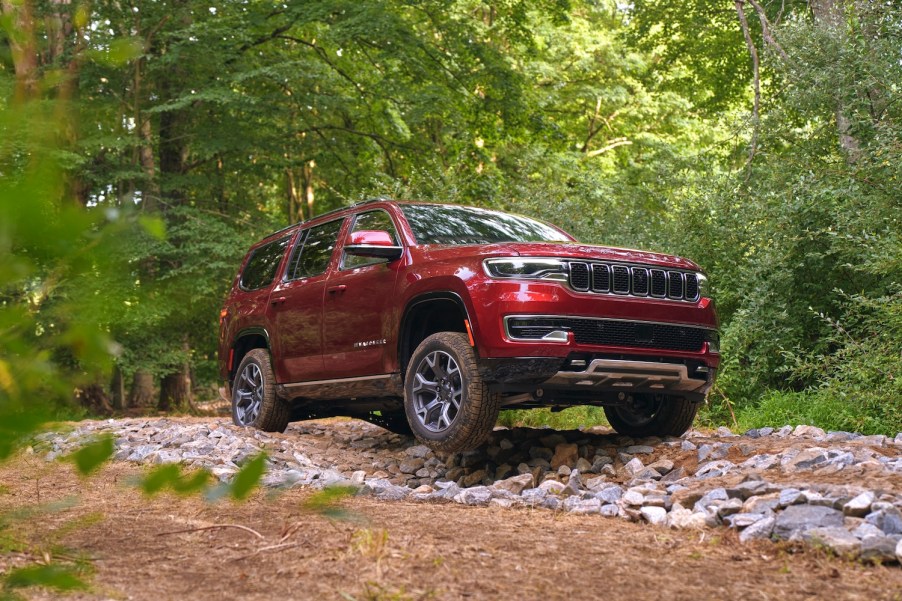 A red 2022 Jeep Wagoneer full-size luxury SUV off-roading in the woods