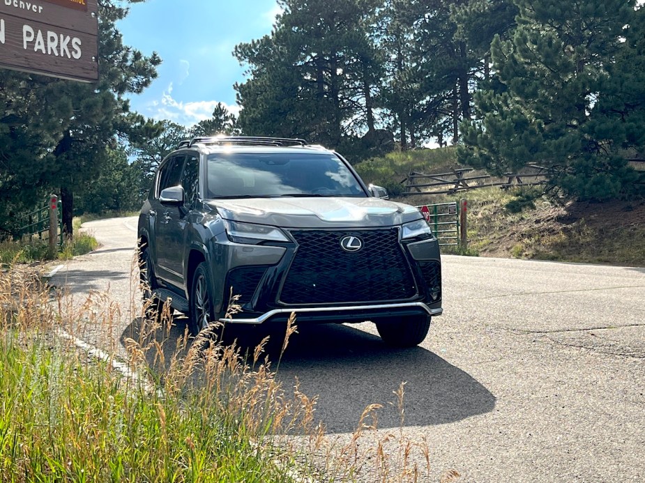 A front corner view of the Lexus LX 600 next to a park sign.