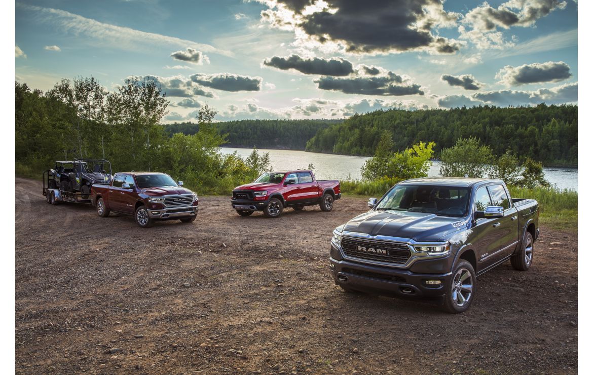 Three Ram trucks parked near a lake. 